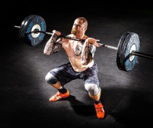 Man in a front rack position with a barbell and weights