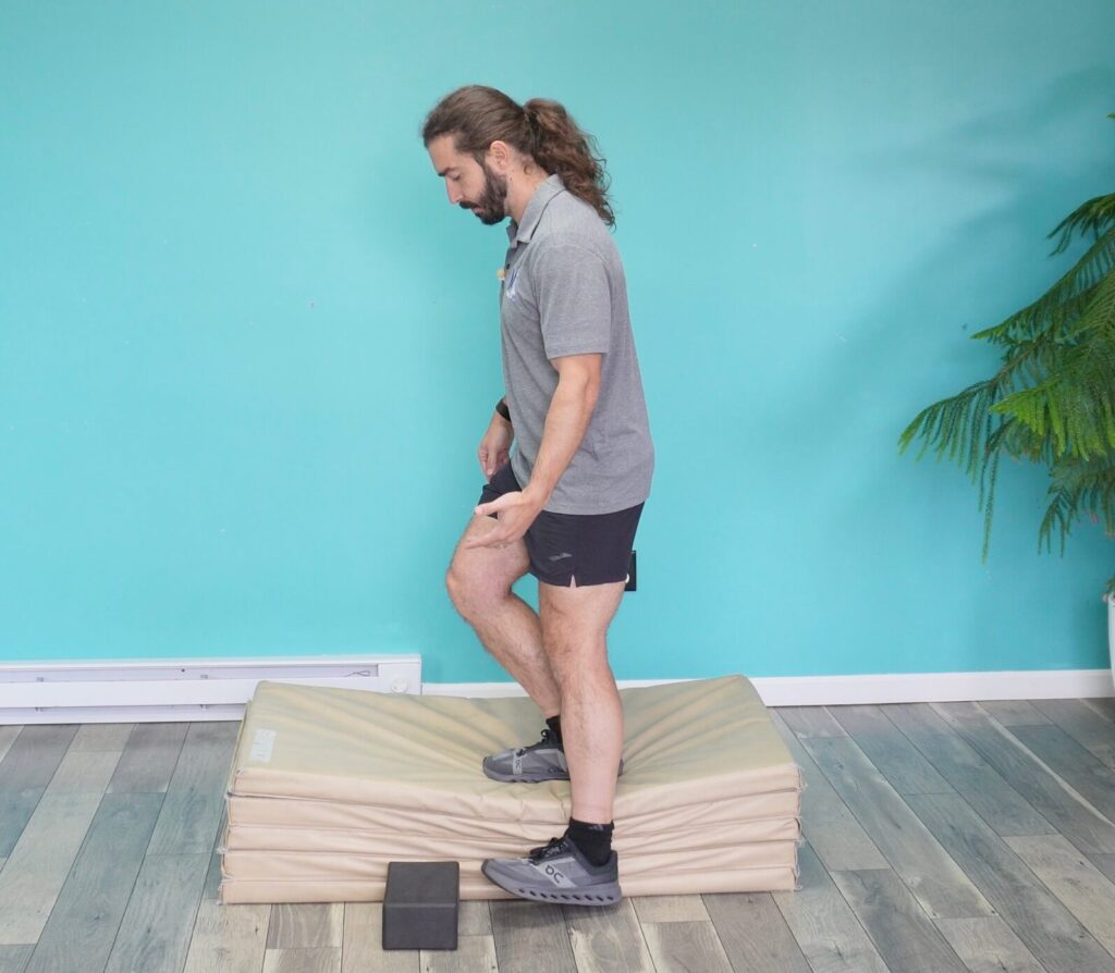 dr. john demonstraing the lateral step down which is a step down exercise variation. he is lowering his left leg to touch the ground from a side standpoint