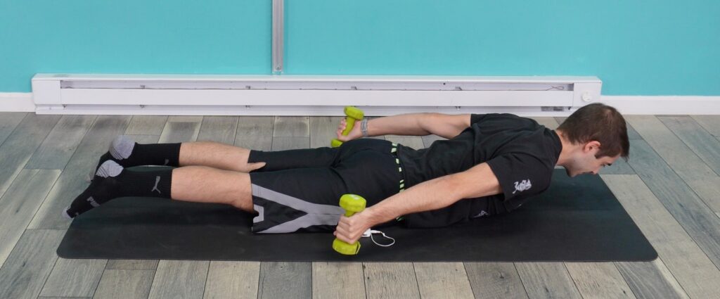 Dr. Jon demonstrating the prone arm sweeps laying on his stomach with his arms by his sides