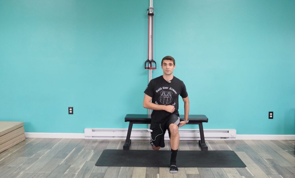dr. Jon with his left foot forward squatting into a bulgarian split squat