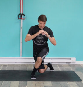 Dr. Jon doing a curtsy squat with his left leg in front, right leg back and slightly behind