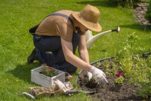 A woman on her knees bent over gardening in a garden bed