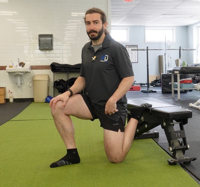 Dr. John with his foot up on a bench demonstrating the couch stretch