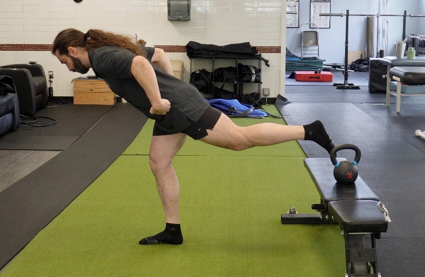 with his right foot planted on the ground dr. john is hinging forward from his hips to lift the left leg off the ground as part of how to strengthen your hip flexors for running