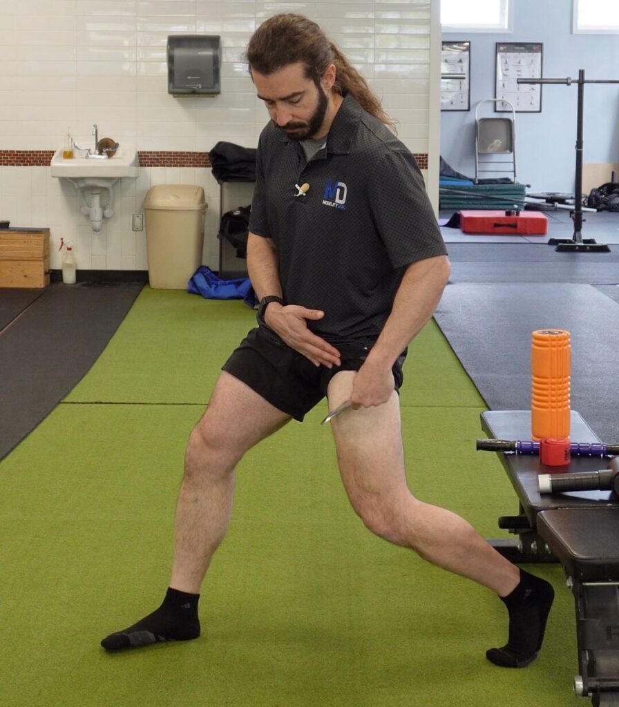 Dr. John using the muscle scraper on his hip flexor as a tool to release tension