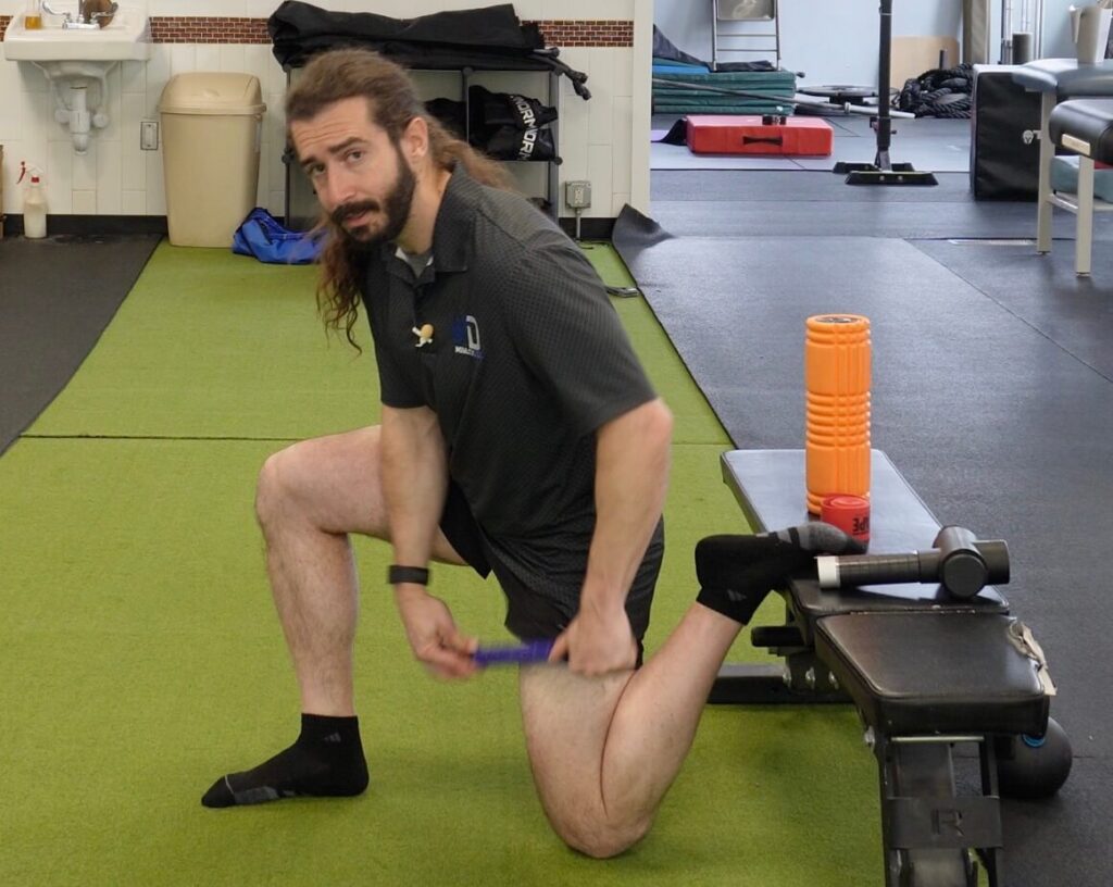Dr. John using the stick as a tool to release hip flexor tension