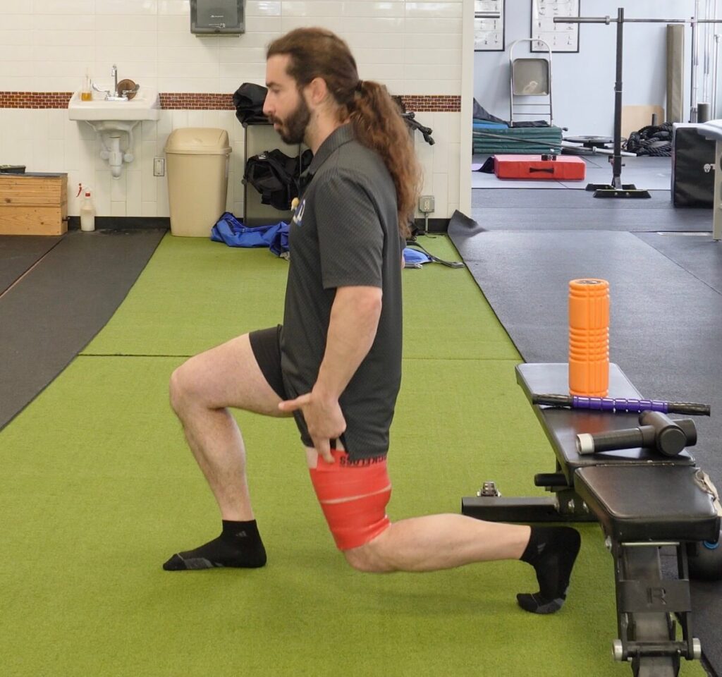Dr. John doing a split squat with muscle floss around his quad